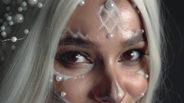 Sanatçı ustasının mükemmel çalışması, beyaz saçlı, kahverengi gözlü kız kameraya bakıp flört ediyor, taze, hafif, sağlıklı ciltte makyaj yapıyor, yaratıcı görüntüler için kozmetik ürünler pazarlıyor..
