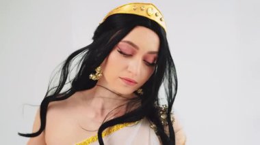 Elinde dans eden ipek kumaş, elinde seksi gözler mükemmel cilt güzel yüz pembe makyaj portresi kraliçe esmer saçlar rüzgarda uçan kız kameraya bakıyor. Antika tarzı altın taç.