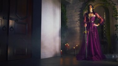 Elinde kılıç tutan Gotik Kraliçe Fantezi sanat portresi. Güçlü savaşçı kız peri elf prenses gülen elf kulakları. Başında siyah altın taç var. Ortaçağ silah bıçağı. Gece Odası Tahtı