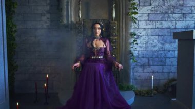Sanat portresi fantezi kadın kötü elf kraliçe tahtta oturur, koyu mor uzun elbise. Seksi cadı elf kızı, sivri kulaklı. Gotik vampir prenses, altın taç. Eski tarz gece odası dumanlı.