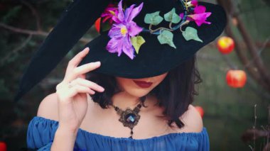 Yakın plan seksi yüz, mavi göz yaratıcı sanat makyajı, kameraya bakan kız. Fantezi Kadın Ortaçağ Cadısı Cadılar Bayramı Kara Koni Karnavalı Mor Şapka Elbisesi