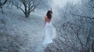 Genç kadın geri döndü. Karlı yolda yürüdü. Ormanda kış sisi vardı. Buz tutmuş güzel ağaçlar. Esmer, gevşek saçlı. Çıplak seksi sırt. Beyaz, uzun bir gelinlik. Model dikiz görüntüsü