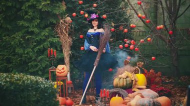 Cadılar Bayramı portresi mutlu fantezi kadın elinde süpürgeyle dans ediyor. Klasik mor kostüm ortaçağ elbisesi, sanat uzun koni şapkası. Sihirbaz bayan model seksi kız pozu. sonbahar arkaplanı.