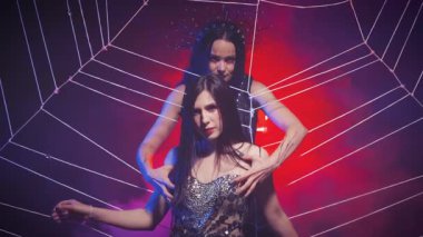 Fantezi kraliçesi seksi gümüş elbise. Gotik kötü cadı, ağ örüyor. Gotik kötü vampir korkmuş prensese dokunuyor örümcek ağıyla, pençeleriyle. Cadılar Bayramı yaratıcı tatil konsepti