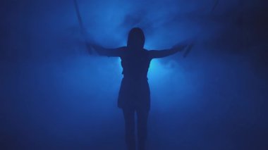 Siyah siluet fantezi kadın suikastçı iki katana kılıcı tutuyor. Siyah arka plan mavi ışık tam duman. Peri asker kız elini kaldırdı. Silahlı seksi kız prenses. Ortaçağ silahı