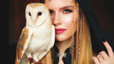 Sanat portresi fantezi gotik mistik kadın elinde beyaz ahır baykuşu, yüzünün bir parçasını saklıyor. Fantezi Elf sarışın büyücü kız seksi gözler kameraya bakan vahşi kuş kanatları. sihirbaz başlığı.
