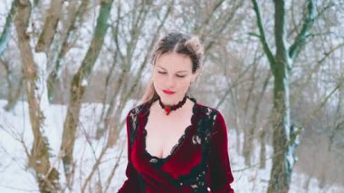 Fantezi mutlu kadın kraliçe kar altında kış ormanlarında yürüyor. Soğuk doğa, beyaz kar, siyah ağaçlar. Kız prenses güzel gülümseyen yüz mükemmel soluk ten, kırmızı dudaklar. Klasik tarz, uzun ve kalın elbiseli bayan 4k