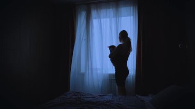 Siyah, karanlık, yalnız bir kadın, elinde kedisi olan bir kadın pencereye bakıyor. Ruh hali bunalımı, üzüntü hissi. Yalnız Üzgün Kız geri görüşü. Rüzgâr perdeleri uçurur, sallanır beyaz kumaş, rahat bir oda.