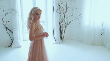 Prenses üzgün. Beyaz arka plan klasik ev odası iç mekan çocukları renkli oyuncaklar. Zarif bej rengi, uzun, lüks, seksi elbise treni. Kraliçe kadın saç stili dalgalı sarı saçlar. Taçlı küpeler inciler.