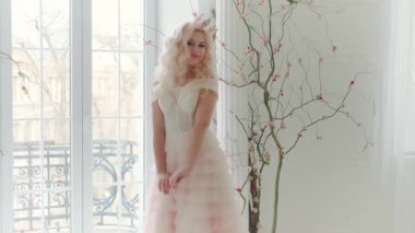 Genç, güzel, seksi, romantik kadın klasik odada gülümsüyor, siyah ağaç dalları suni çiçekler. Lüks balo zarif elbisesi. Beyaz uzun dalgalı saçlar klasik taç. Hassas doğal makyaj.