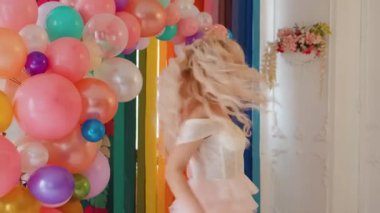 Genç, romantik, mutlu bir kadın prensesin portresi. Güzel bayan kraliçe neşeyle gülüyor, gülümsüyor. Çok renkli parlak balonlar. Uzun kıvırcık sarı saçlar dalgalanıyor. Kraliyet mahsulü taç