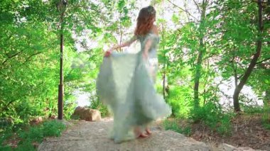 Lüks, görkemli, sulu elbiseli genç bir kadın rüzgarda dalgalanan bir tren fırlatıyor. Arkadan, yüzü olmadan çekim yapmak. Kraliyet Parkında Gizemli Prenses