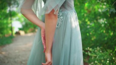 Lüks, turkuaz, uzun bir gece elbisesi içinde kendini okşayan genç bir prenses. Arkadan çekim yapıyorlardı. Rüzgarda dalgalanan saçlar. Tatlı surat. Arka plan yeşil yaz parkı.