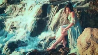 Islak su rengi elbise giyen genç çekici bir kadın taşlara oturur ve çıplak bacağını okşar. Yumuşak, kırılgan, ince, nehir perisi, tropik bir şelalenin yanında dinleniyor. Parlak güneşli bir gün. Rüya Prensesi..