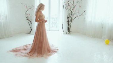 Prenses üzgün. Beyaz arka plan klasik ev odası iç mekan çocukları renkli oyuncaklar. Zarif bej rengi, uzun, lüks, seksi elbise treni. Kraliçe kadın saç stili dalgalı sarı saçlar. Taçlı küpeler inciler.