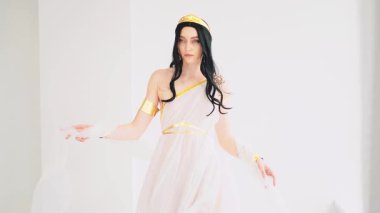 Elinde dans eden ipek kumaş, elinde seksi gözler mükemmel cilt güzel yüz pembe makyaj portresi kraliçe esmer saçlar rüzgarda uçan kız kameraya bakıyor. Antika tarzı altın taç..