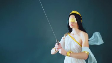 Yunan adalet tanrıçası fantezi portresi Themis 'i kör etti, savaş antik çelik kılıcı elinde tutuyordu. İpek beyaz elbise, altın aksesuarlar, klasik kostüm. Uzun saç kumaşı rüzgarda uçuşuyor..