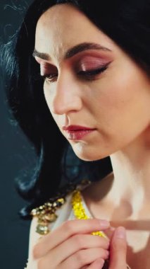 Fantezi sanat portresi parlak güzellik Yunan tanrıça kadın manken pozu veriyor. Afrodit kız seksi kraliçe. Beyaz elbiseli, altın kaplama, esmer, uzun saçlı, rüzgârda çırpınan sinek. Siyah stüdyo arka planı