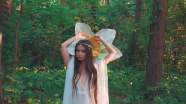 Fantezi portresi genç kadın elf, başında gümüş taç uzun siyah saçlar. Beyaz ipek elbiseli, geniş kollu, çekici prenses kız. Moda modeli, peri masalı yaz ormanı.