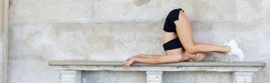 Siyah bluzlu sarışın sporcu, şortlu ve beyaz spor ayakkabılı. İtalya 'da taş bankta antrenman yapıyor. 