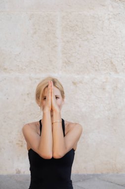Sarışın kadın Venedik 'te meditasyon yaparken yüzünü elleriyle kapatıyor. 