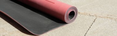 pink fitness mat with shadow on asphalt sidewalk on urban street in sunny day, summertime, banner  clipart