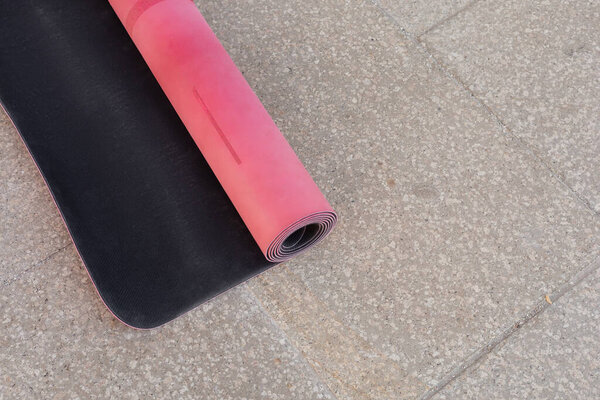 Top view of pink fitness mat on asphalt sidewalk outdoors, copy space, urban lifestyle 