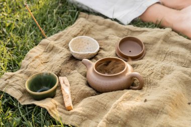 aromatik palo santo çubuğu ve seramik çaydanlık kesilmiş yoga adamının yanında çimenlikte oturuyor.