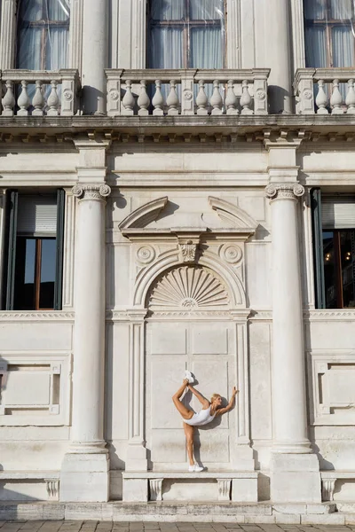 Спортсменка в белом купальнике и кроссовках на скамейке у древнего здания в Венеции — стоковое фото