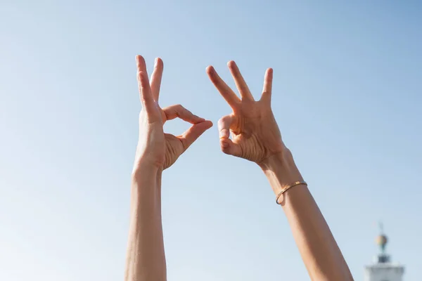 Cropped view of woman showing okay gesture with sky at background — Stock Photo