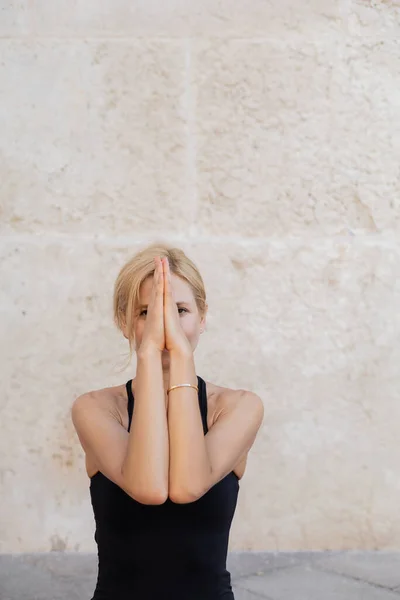 Blonde woman covering face with hands while meditating outdoors in Venice — Stock Photo