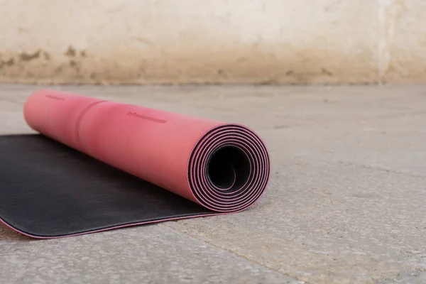 Close up view of pink and black fitness mat on sidewalk outdoors, copy space, urban lifestyle — Stock Photo
