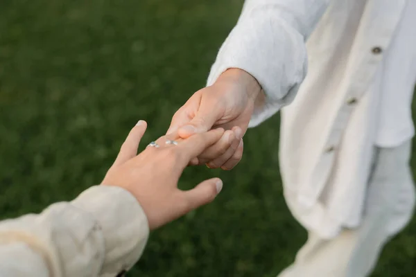 Visão parcial do homem de ioga em roupas de linho branco segurando a mão da jovem mulher ao ar livre — Fotografia de Stock