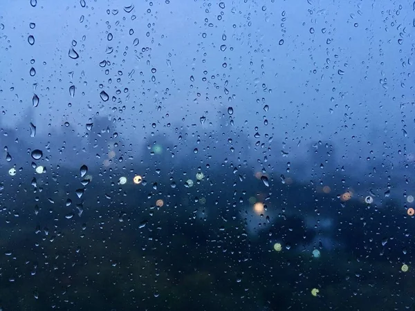 雨滴落在玻璃上 以城市景观为背景模糊 背景城市灯火通明 雨季夜晚的城市生活 抽象的城市背景 — 图库照片