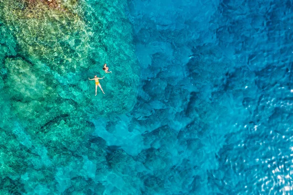 在希腊罗得岛 一对年轻夫妇在珊瑚礁上方浮潜到水晶般清澈的水晶区深处的空中照片 一对夫妇在水晶般清澈的水中潜水的空中无人驾驶图片 — 图库照片