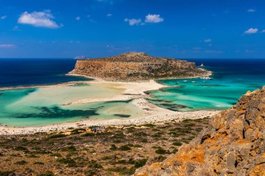 Yunanistan 'ın Girit kentindeki Balos Gölü ve Gramvousa adasının muhteşem manzarası. Kaptan Tigani ortada. Yunanistan 'ın Girit adasındaki Balos plajı. Turistler Balos sahilinin berrak sularında rahatlar ve banyo yaparlar..