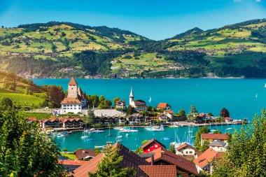 Günbatımında İsviçre 'nin Bern kantonunda bulunan Thun Gölü kıyısındaki Spiez Kilisesi ve kasaba manzarası, Spiez, İsviçre. İsviçre 'nin Bern kantonundaki Thun Gölü kıyısındaki Spiez şehri..