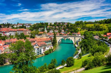 Bern eski şehir merkezi ve Aare, Bern nehri üzerindeki Nydeggbrucke köprüsü manzaralı. Bern, güneşli bir günde Aare Nehri 'nin şehrin etrafında aktığı eski bir kasaba, Bern, İsviçre.