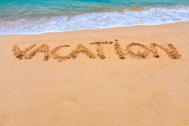 Plajda bir tatil mesajı. Kumlu bir tropik plajda yazılmış bir tatil. Sahildeki kumlara yazılmış 