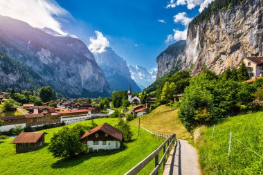 Amazing summer landscape of touristic alpine village Lauterbrunnen with famous church and Staubbach waterfall. Location: Lauterbrunnen village, Berner Oberland, Switzerland, Europe. clipart