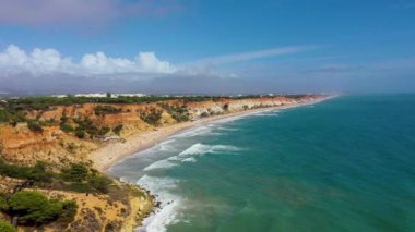 Praia da Falesia plajı, Algarve, Portekiz. Praia da Falesia, Algarve Portekiz 'de beyaz kumsal ve turkuaz su ile. Praia da Falesia, Algarve, Portekiz 'deki renkli turuncu kayalıklar.