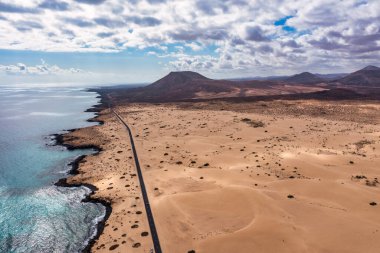 Fuerteventura, Corralejo kum tepeleri doğa parkı. Güzel Hava Çekimi. Kanarya Adaları, İspanya. Gün batımında kum tepelerinin arasından geçen boş bir yolun havadan görüntüsü. Fuerteventura, Kanarya Adaları, İspanya.