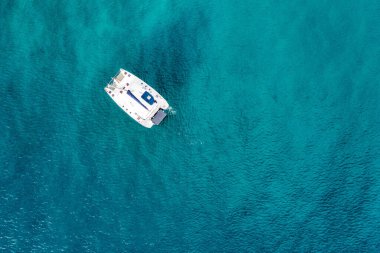 Zümrüt denizdeki demirli yelkenli yatının havadan görünüşü. Bir teknenin havadan görünüşü. Açık deniz sporları, yat. Açık denizde demirleyen yatın havadan görüntüsü. Okyanus ve deniz yolculuğu ve ulaşım