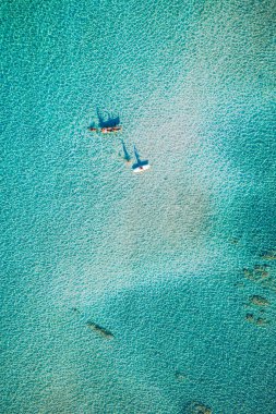 Kayaking in the sea with clear turquoise water. Kayaking, leisure activities on the ocean. Aerial drone bird's eye view of kayak cruising in tropical seascape with turquoise and sapphire clear waters.