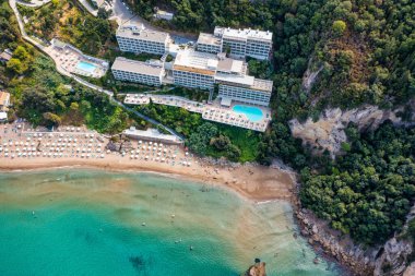 Yunanistan 'ın Korfu adasındaki Agios Gordios egzotik plajı. Agios Gordios plajı, Korfu adası, Yunanistan. Agios Gordios plajının panoramik manzarası, kumlu deniz kıyıları, plaj şemsiyeleri ve şezlonglar..