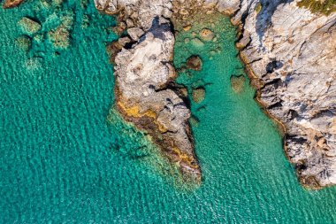 Granit kayalık Akdeniz kıyı şeridi üzerinde açık mavi deniz suyu üzerinde hava fotoğrafı. Okyanus dalgalarının güzel cennet sahillerindeki kayalık kıyılara vuruşunun havadan çekilmiş fotoğrafı.. 