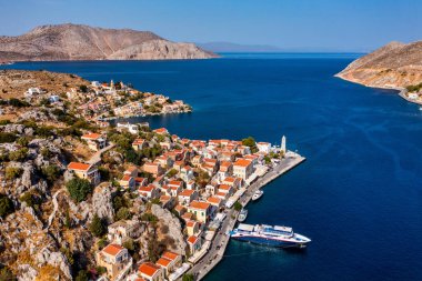 Symi (Simi) ada limanı, klasik gemi yatları, ada tepelerindeki evler, Ege Körfezi manzarası. Yunanistan adaları Rodos adasından tatil turları düzenliyor. Symi, Yunanistan, Dodecanese.