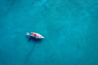 Güneşli bir günde gölde yat. Yelkenli. Deniz yatı, hava fotoğrafçılığı dronu. İnanılmaz bir yat ya da turkuaz ve şeffaf denizi olan bir yelkenli. Mavi göldeki yelkenli teknelerin üst görüntüsü