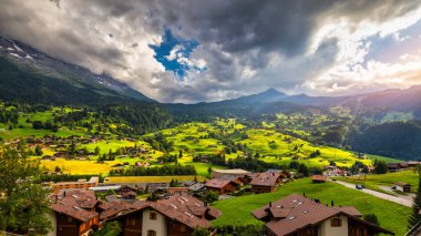 Grindelwald köy manzarası ve yaz İsviçre Alp Dağları manzarası, yeşil tarlalarda ahşap kireçler ve arka planda yüksek zirveler, İsviçre, Bernese Oberland, Avrupa.