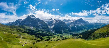 İsviçre 'nin güzel, güneşli bir yaz gününde yemyeşil çayırların açtığı Alpler' in panoramik manzarası. Yaz mevsiminde Alpler 'de çayırları olan İdilik dağ manzarası.